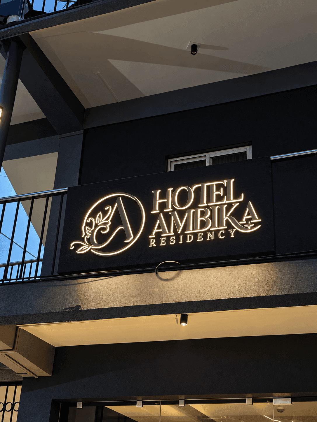 The illuminated Hotel Ambika Residency sign on the building exterior