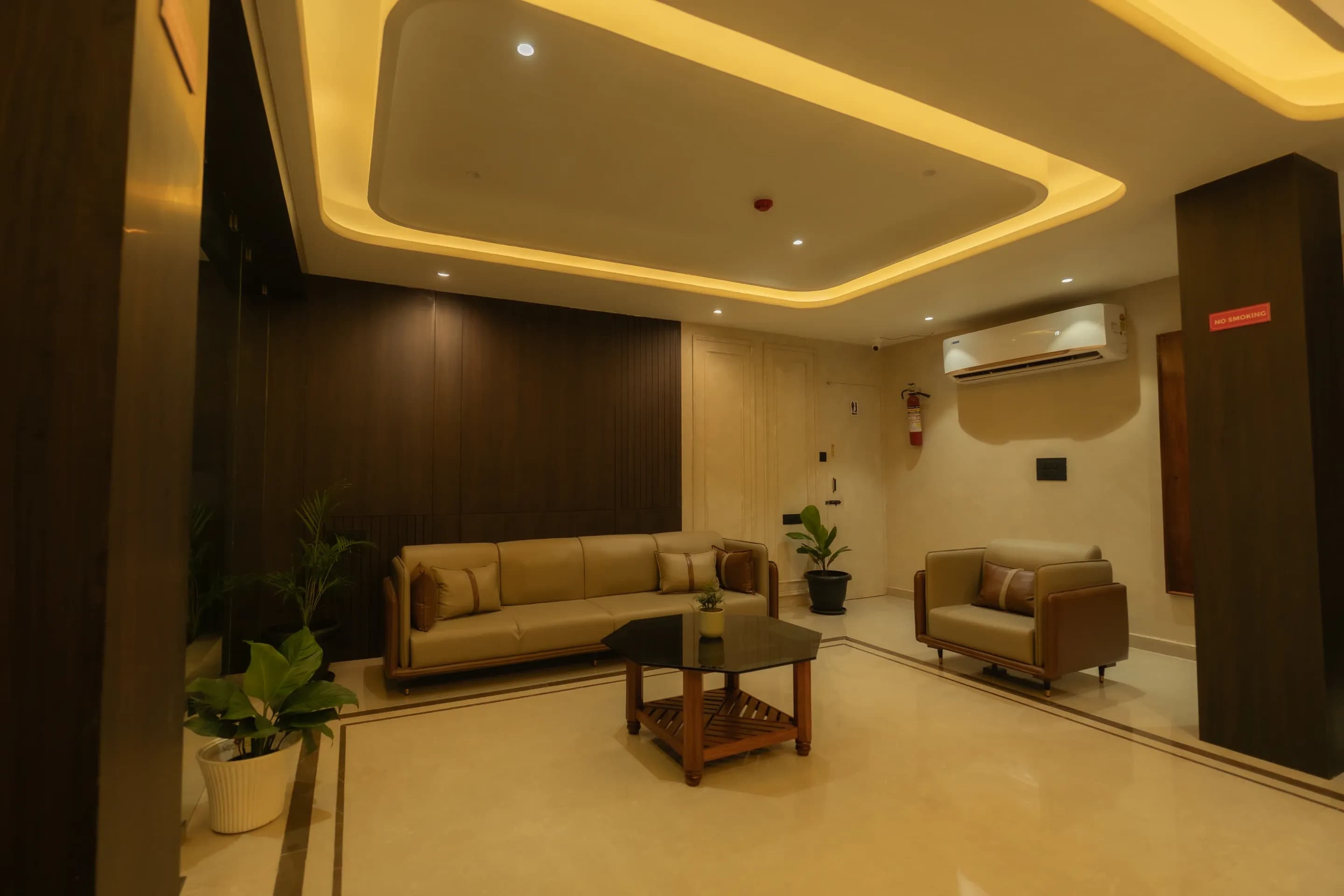 Lobby sofa and armchair around a coffee table beneath warm cove lighting