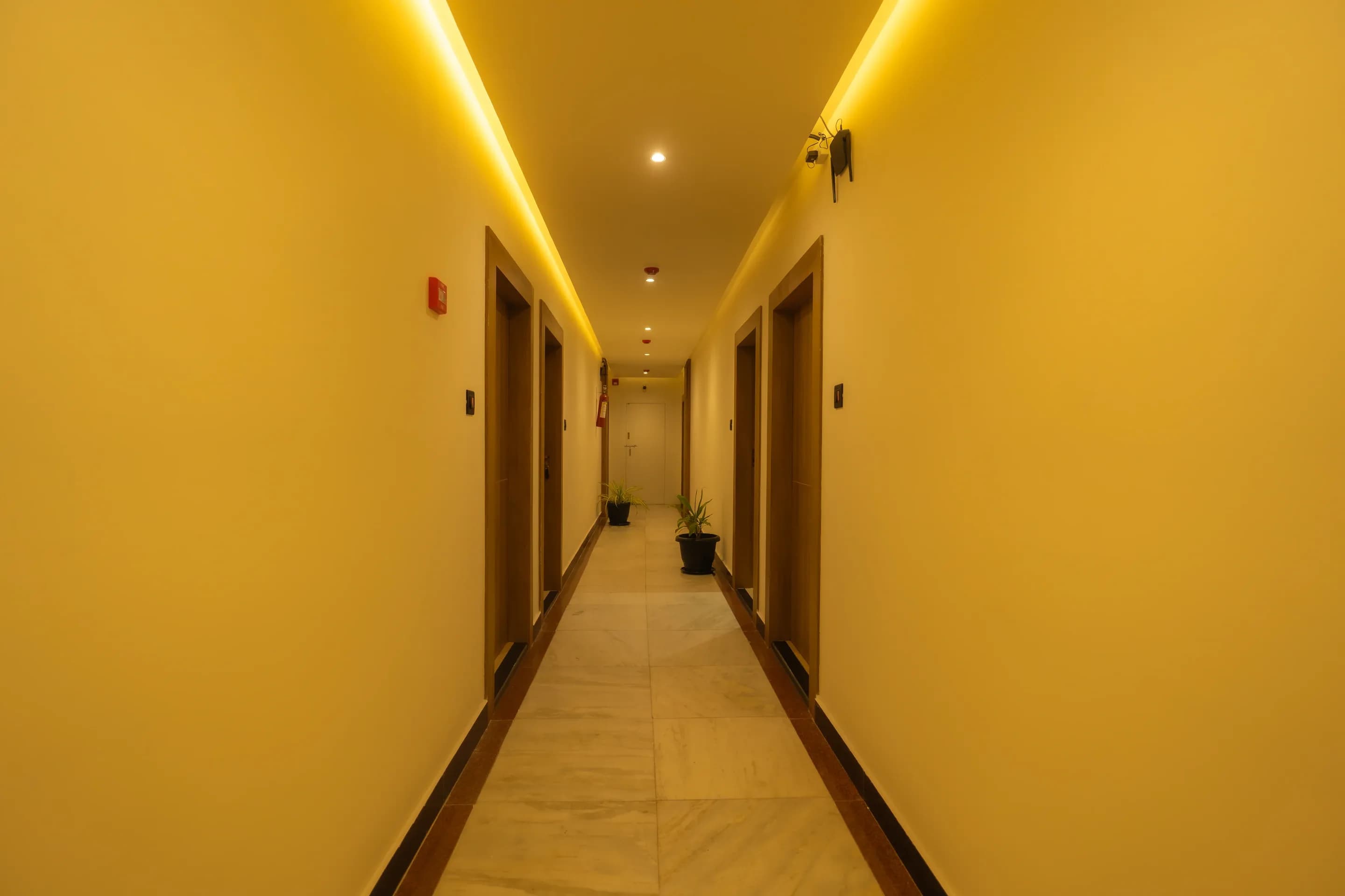 Hotel corridor with guest room doors and warm ceiling strip lighting