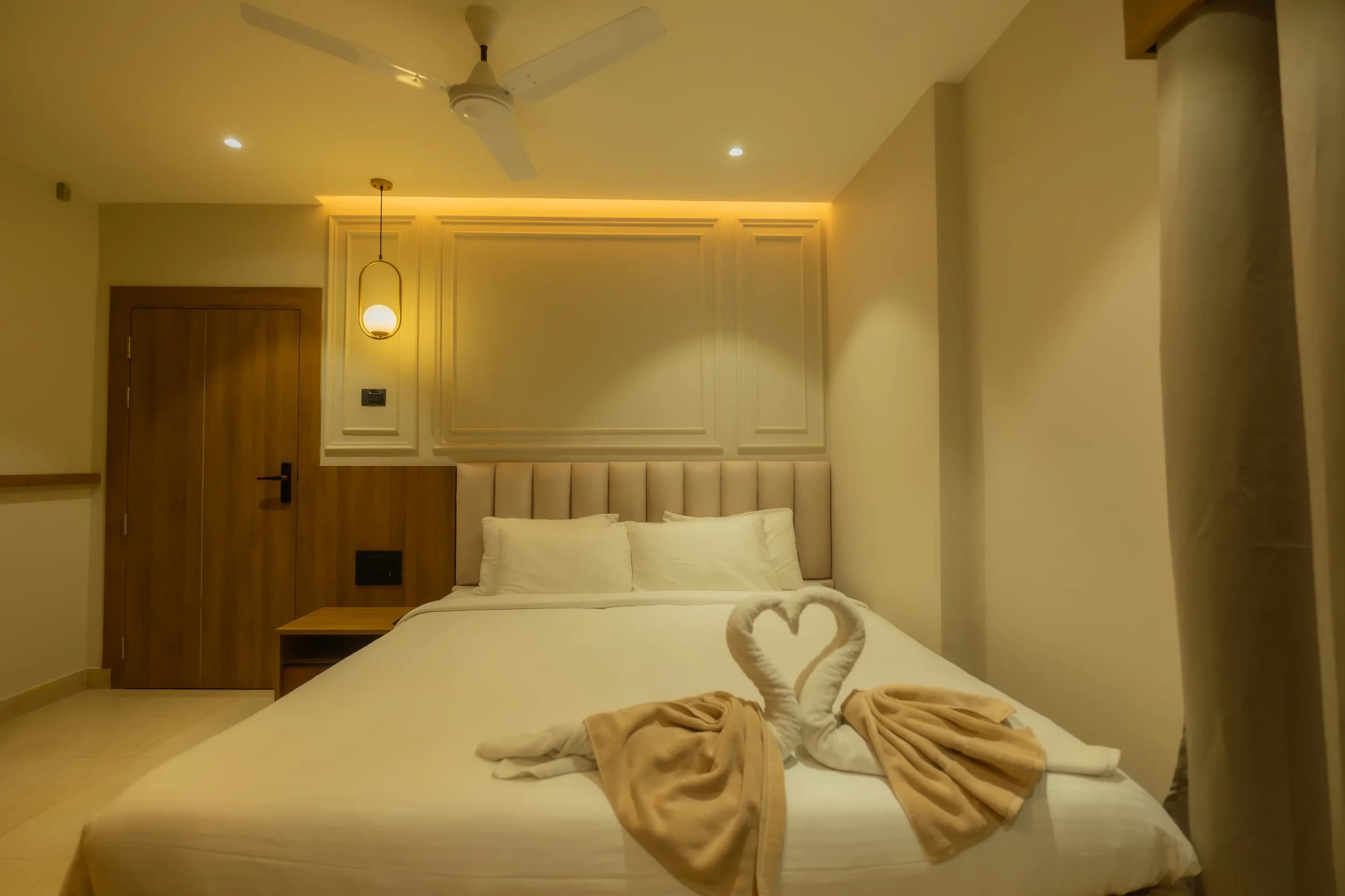 Folded towels arranged on a guest room bed beneath the padded headboard