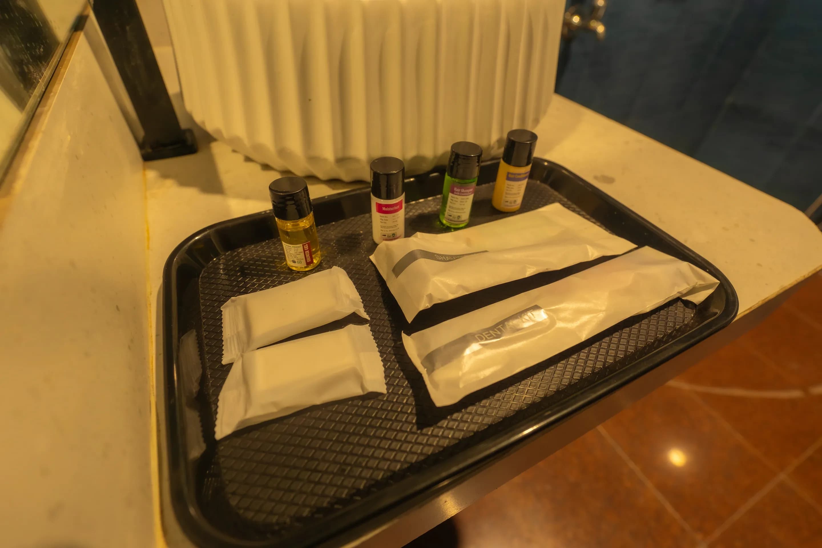 Toiletries and folded towels in a tray beside the bathroom basin