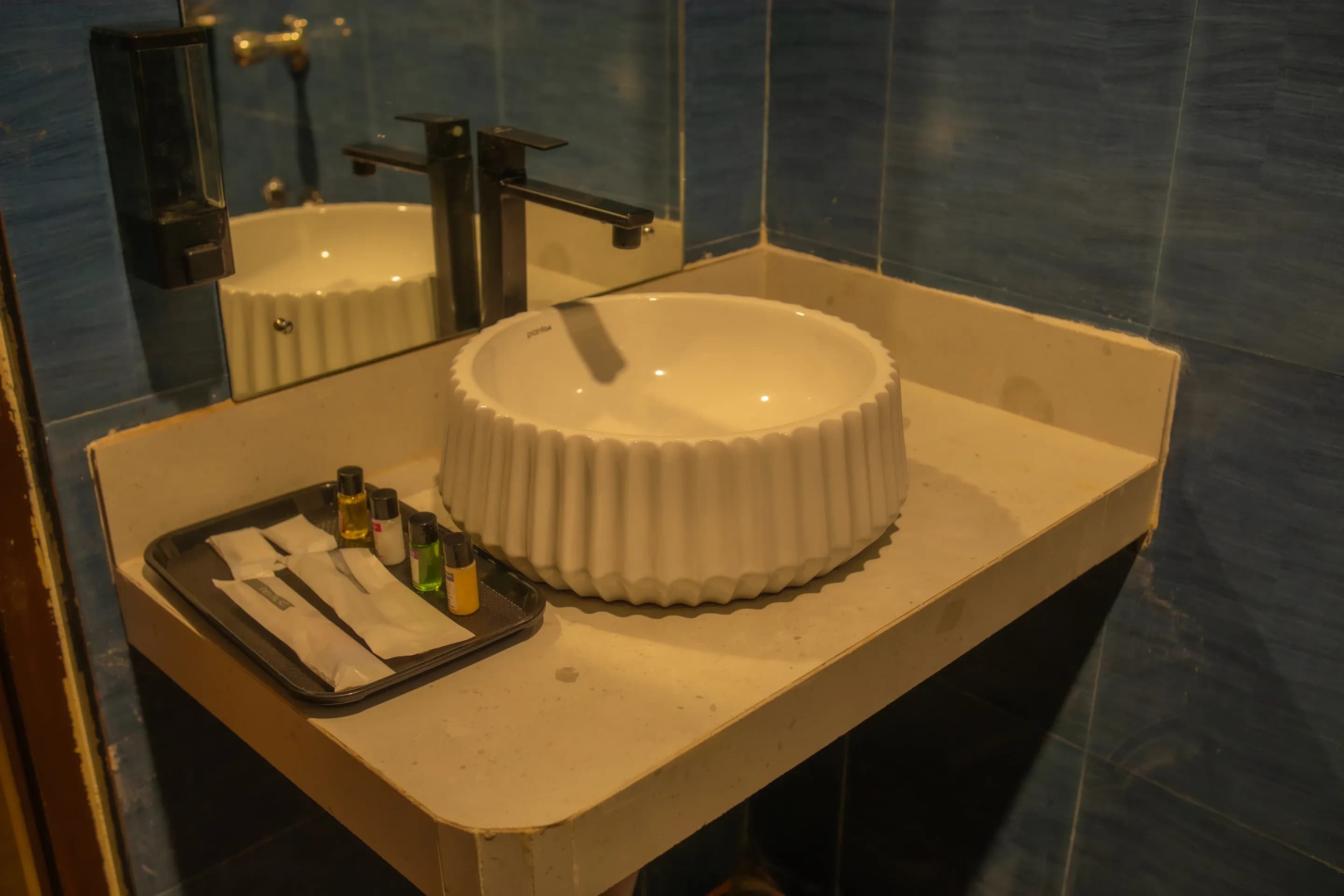 White countertop basin and mirror against blue bathroom tiles