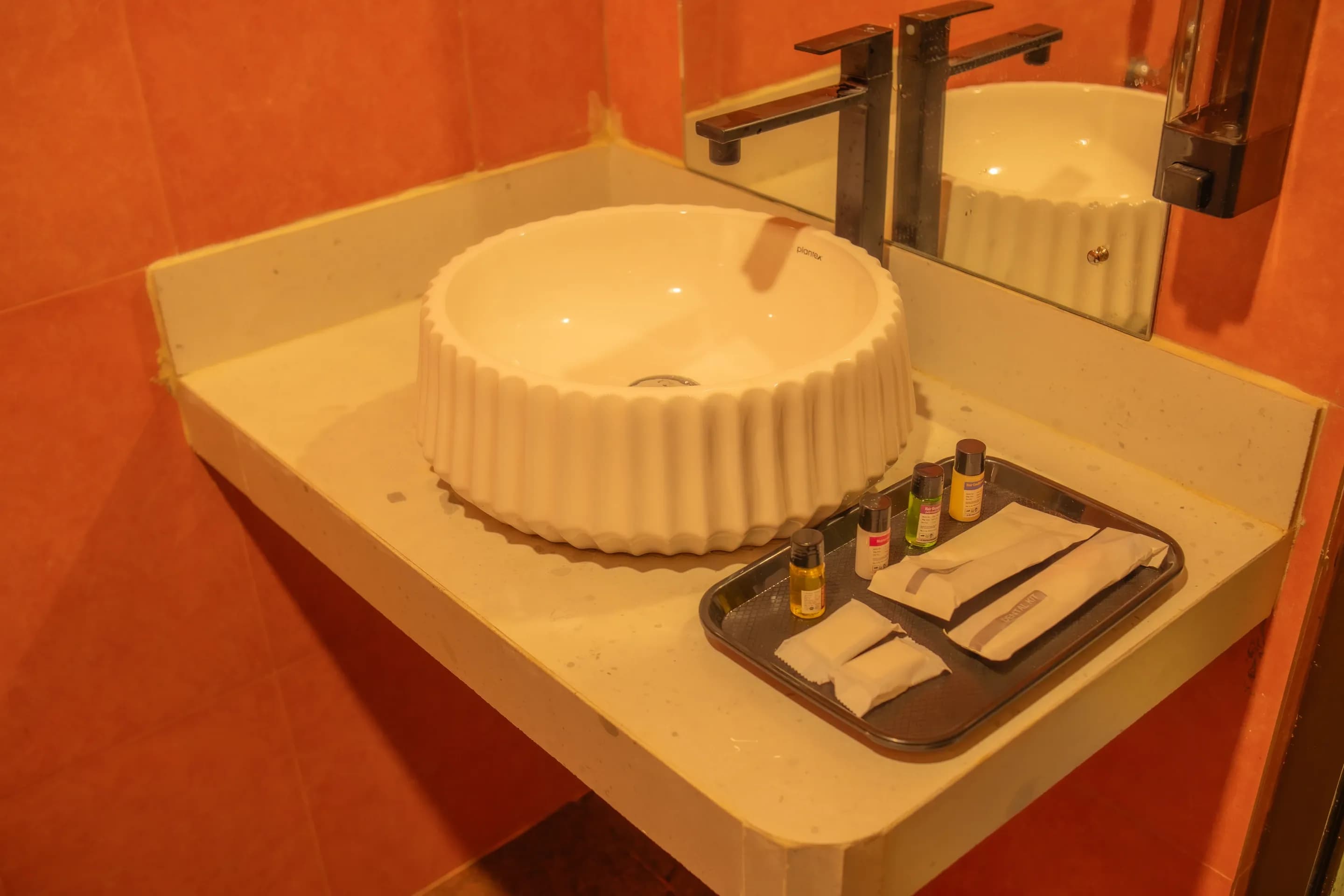 White basin and toiletries on a counter against terracotta bathroom tiles
