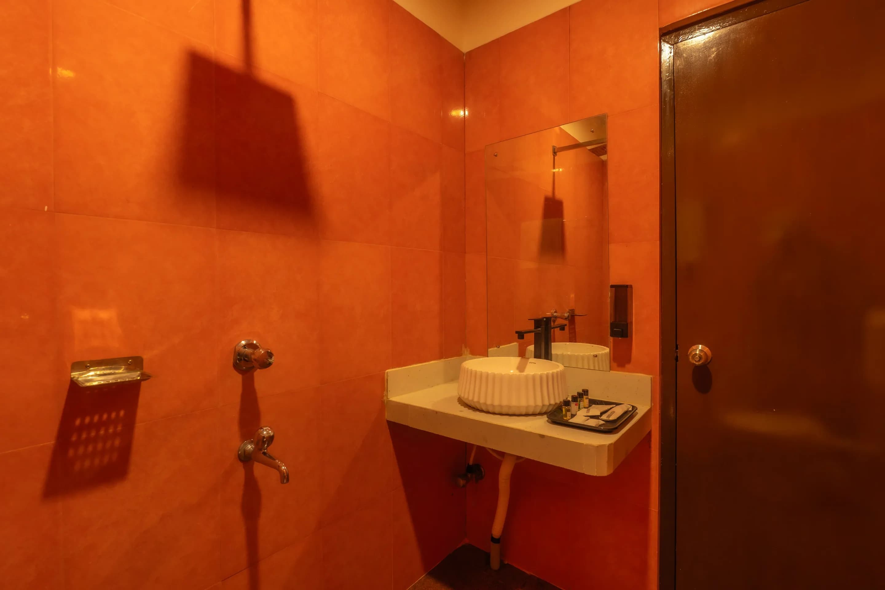 Terracotta-tiled bathroom with a shower, basin and mirror