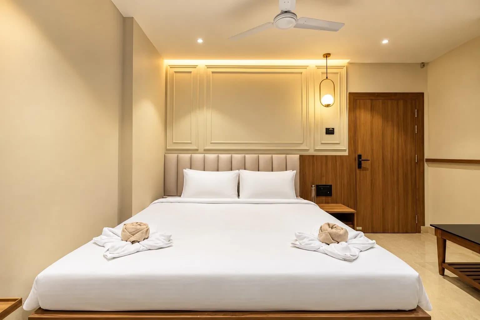 Standard Room bed beneath a lit headboard with a wooden wardrobe beside it