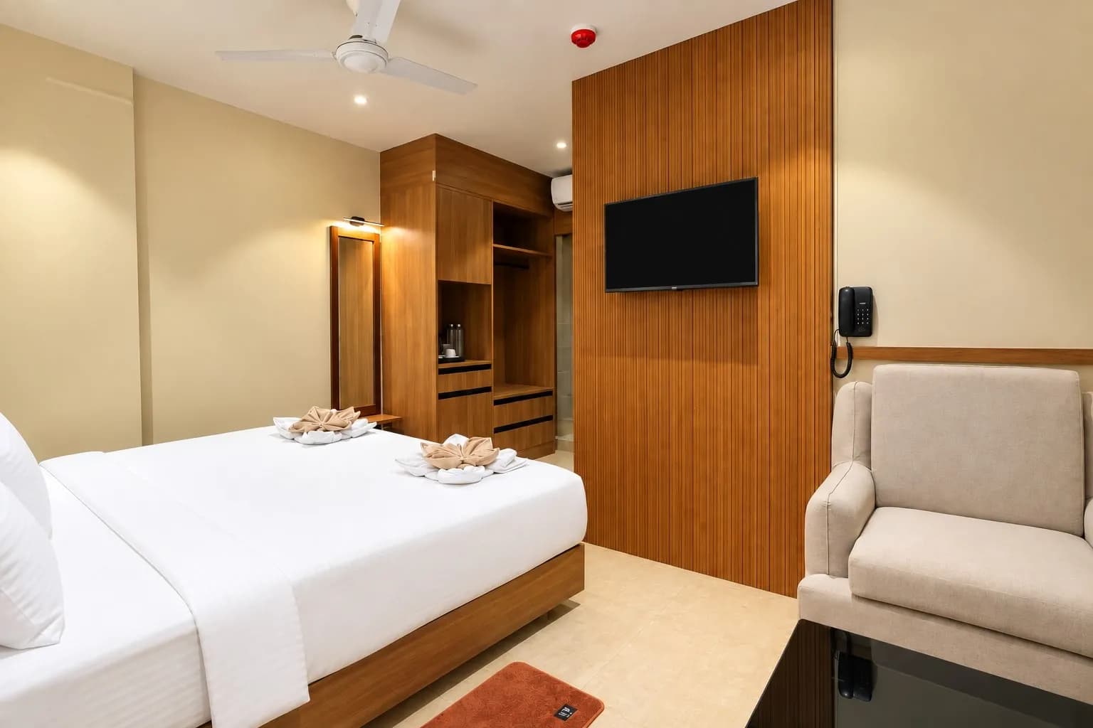 Guest room with a bed, armchair, television and open wardrobe