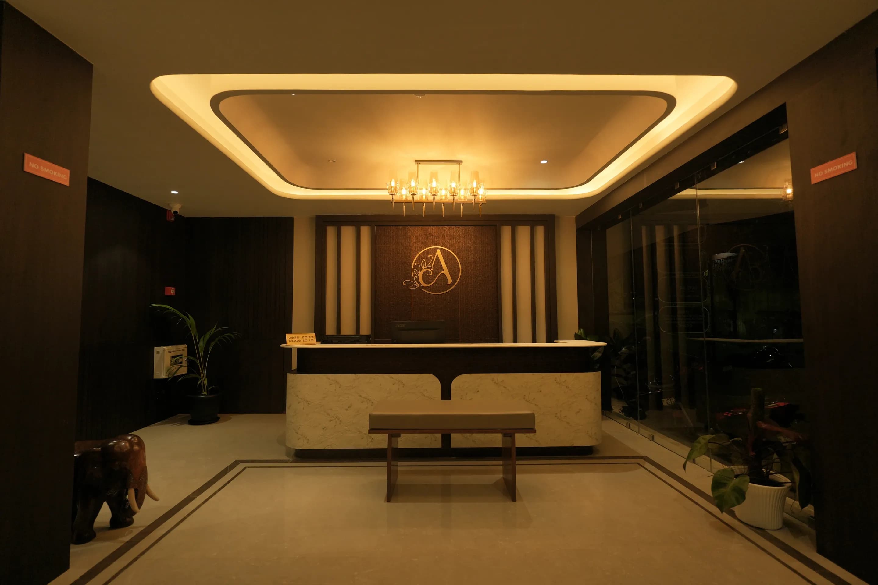 Hotel Ambika reception counter and gold monogram under warm ceiling lights