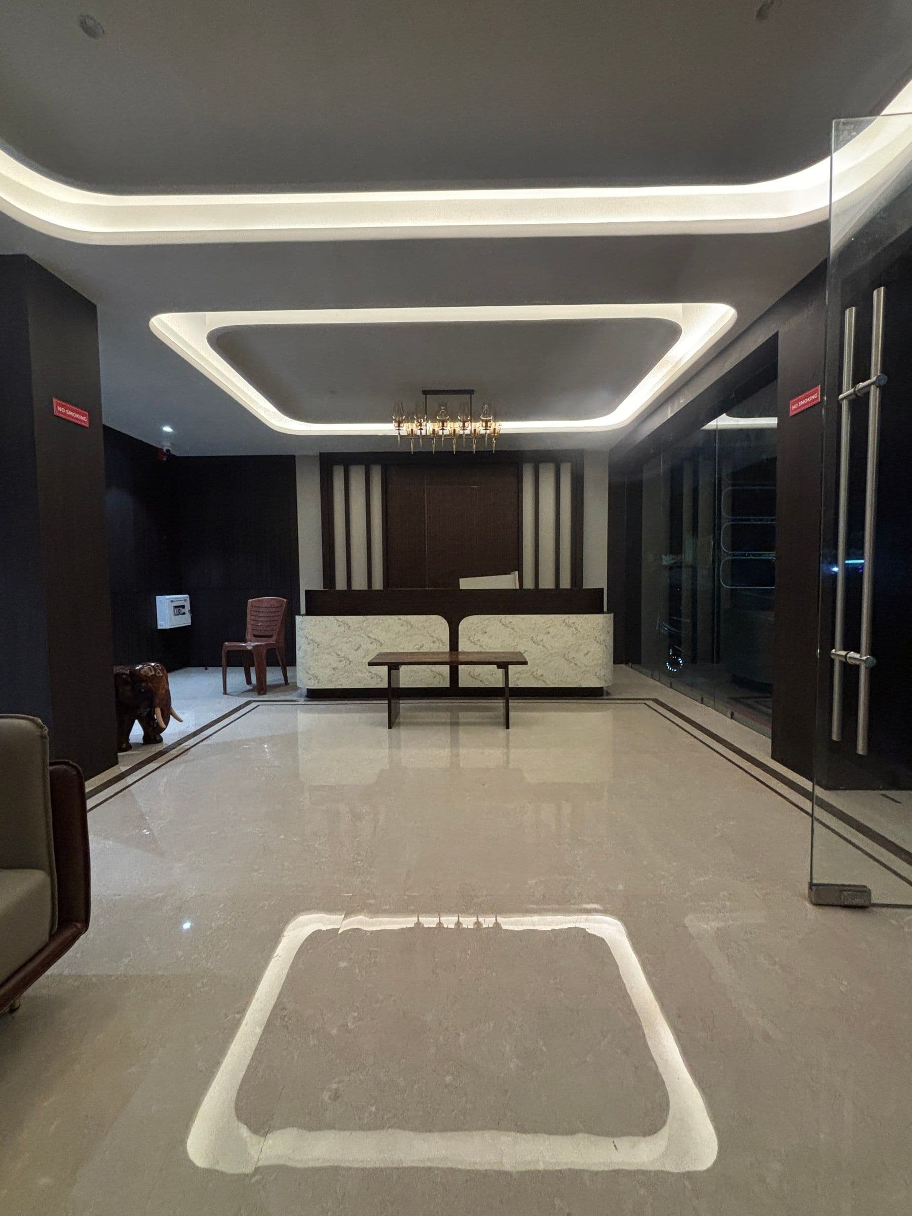 The reception desk and layered ceiling lights at Hotel Ambika Residency