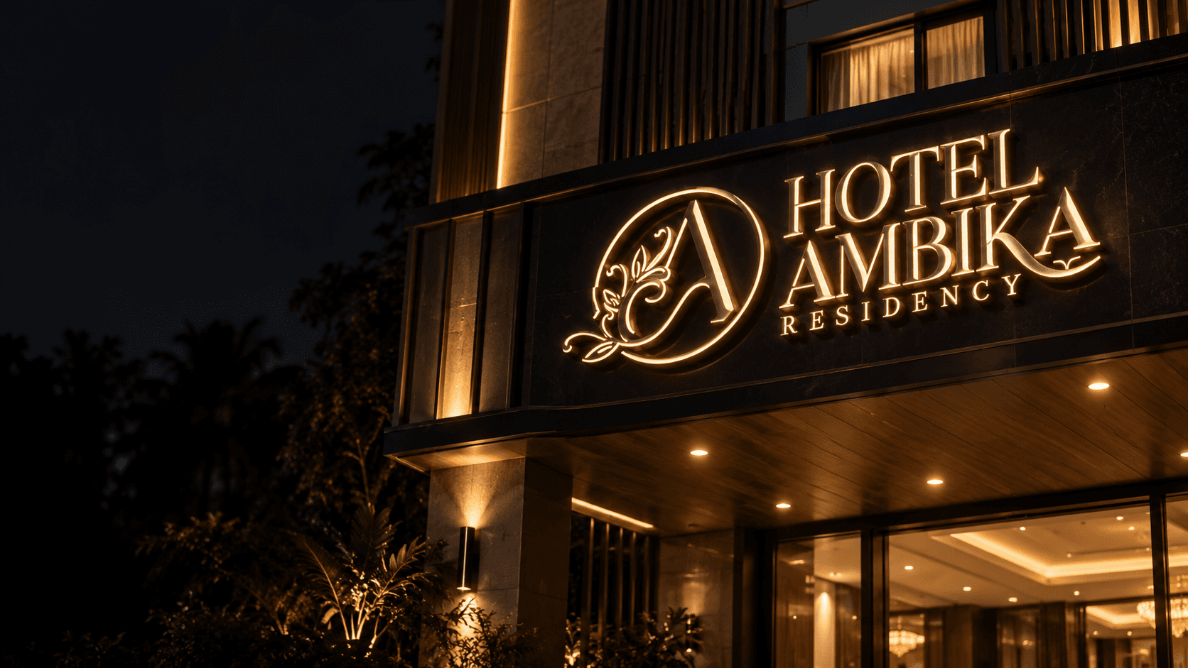 Illuminated Hotel Ambika Residency sign and entrance at night