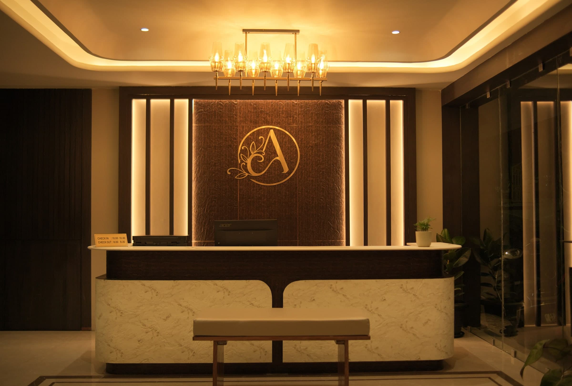 The reception desk beneath the lit monogram wall, where the 24-hour team works