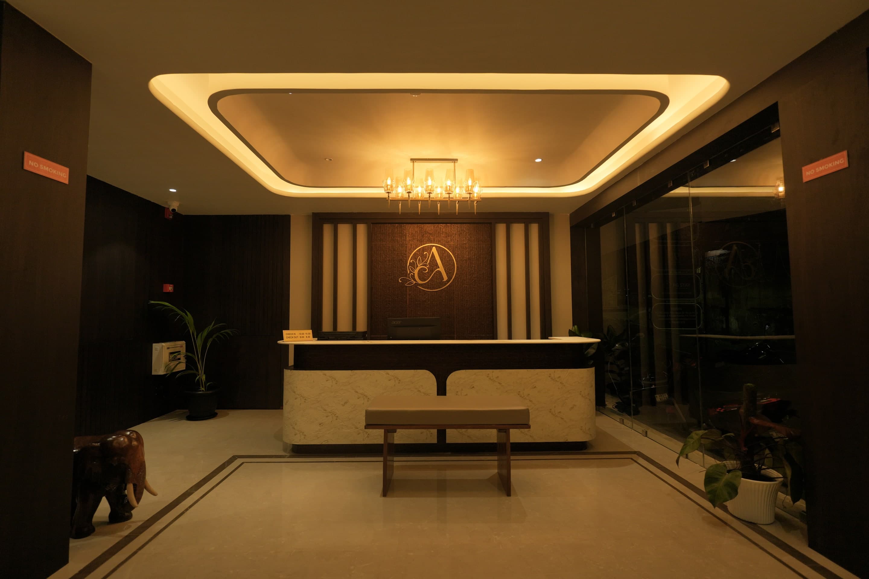 The Ambika reception desk, brass monogram and warm cove lighting