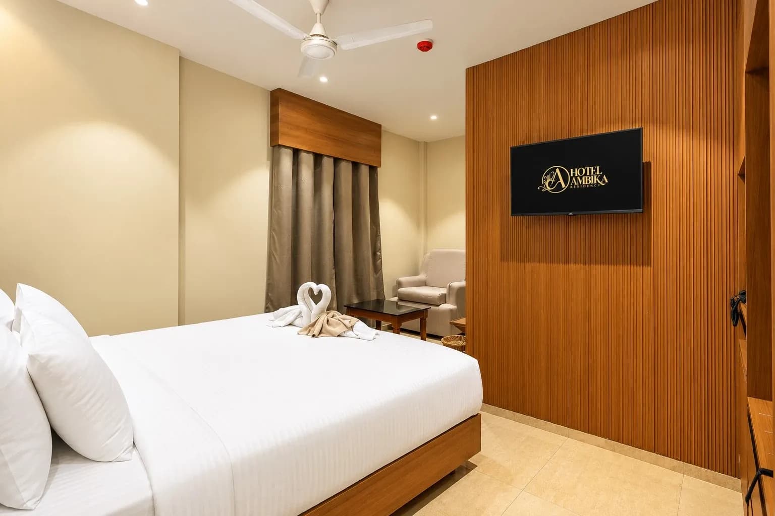 A Premium Room bedroom with a wood-panelled TV wall, bed and seating area