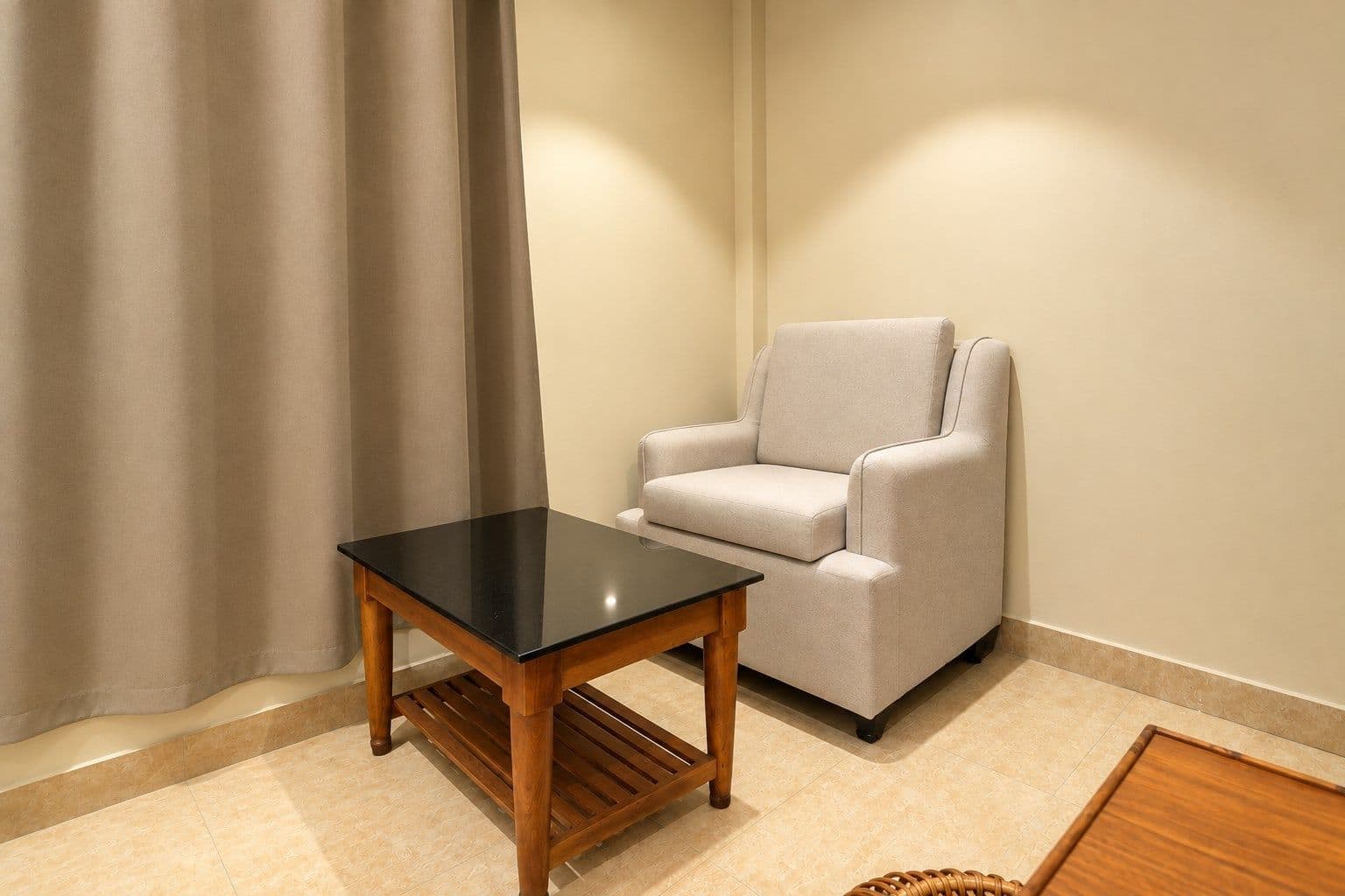 An armchair and side table beside the curtains in a guest room